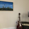 A guitar sitting in front of a painting.