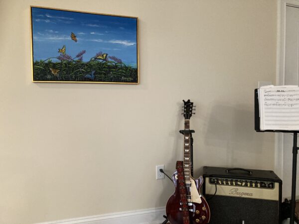 A guitar sitting in front of a painting.