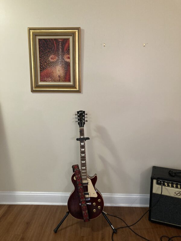 A guitar sitting in front of a painting.