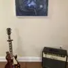 A guitar and an amp in front of a wall.