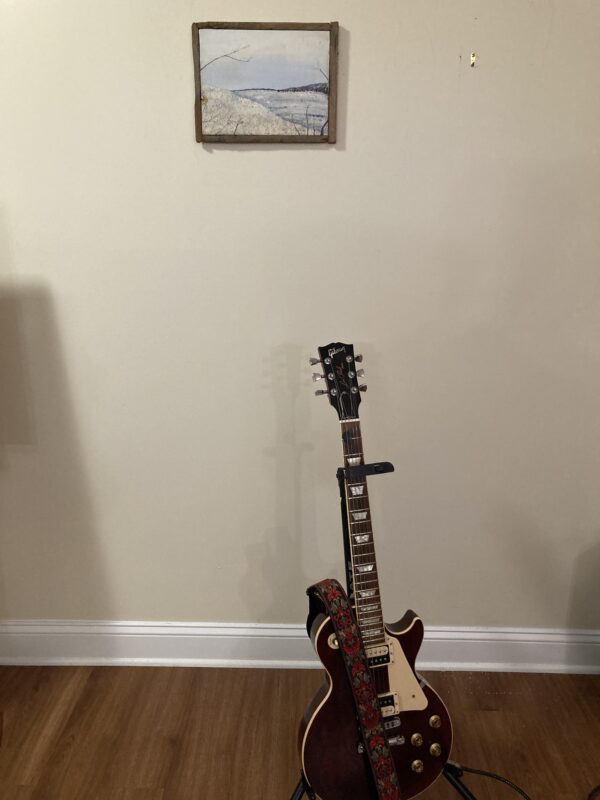 A guitar sitting on top of a wooden floor.