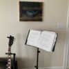 A guitar and a book stand in front of a painting.