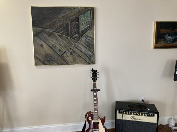 A guitar sitting in front of a painting.