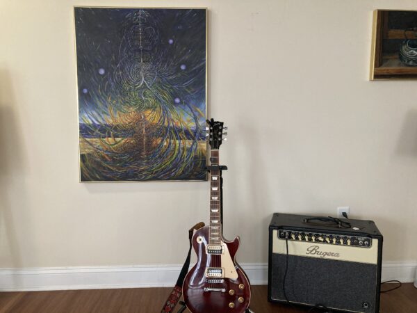 A guitar sitting in front of a painting.